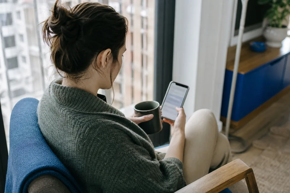 Person reading a job alert email on a phone with morning coffee by a window